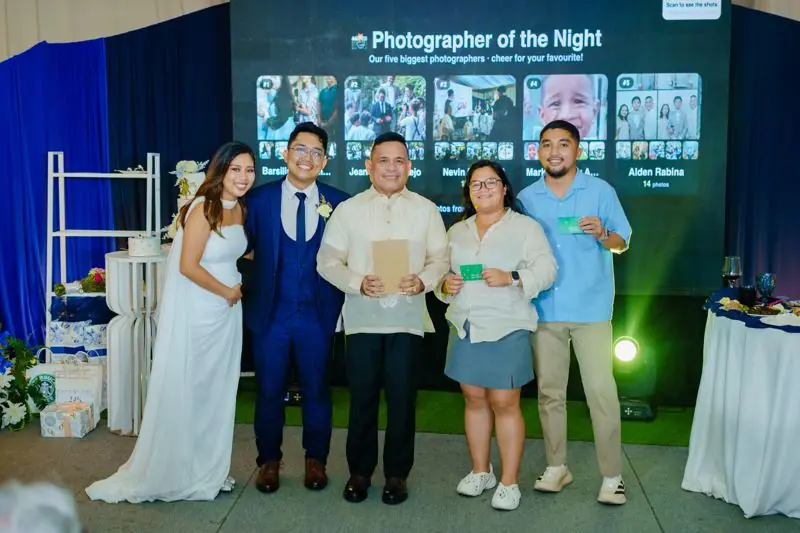 The couple with the photographer of the night winners in front of the big screen